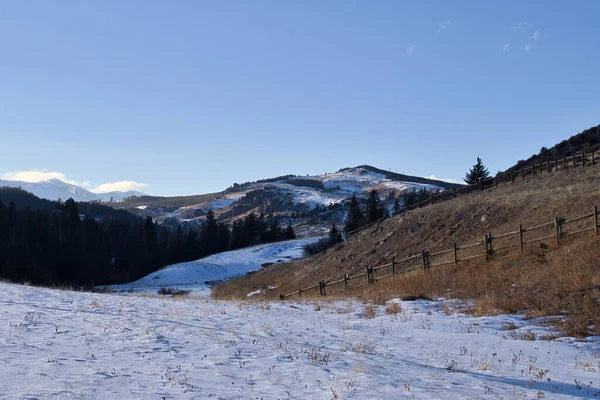 Hills with a fence and snow on the ground in the Bighorn Mountains on a sunny winter day in Wyoming.