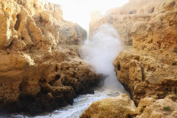 Steam coming off water running over rocks in cliffs in the Atlantic Ocean on a winter day in Carvoeiro, Portutal.
