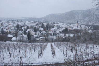 Bad Munster am Stein-Ebernburg, Germany - Febryary 8, 2021: Overlooking vineyard, Bad Munster and Rotenfels covered in snow on a cold, grey, foggy winter day in Rhineland Palatinate, Germany.