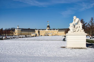 Karlsruhe, Almanya - 12 Şubat 2021: Karlsruhe Sarayı 'nın altındaki heykel soğuk bir kış günü, Almanya' nın Karlsruhe kentinde kar yağarken mavi gökyüzü altında.