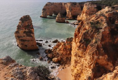 Atlantik Okyanusu 'ndaki kireçtaşı kayalıkları. Yedi Hanging Vadisi' nin sonunda güneşli bir kış gününde Praia da Marinha patikasında..