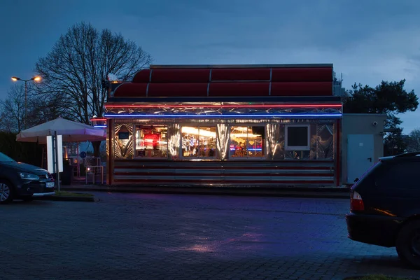 Kaiserslautern, Almanya - 4 Mart 2021: Kaiserslautern, Almanya 'da yağmurlu bir gecede Sam Kullman' s Diner 'in yanında renkli ışıklar.