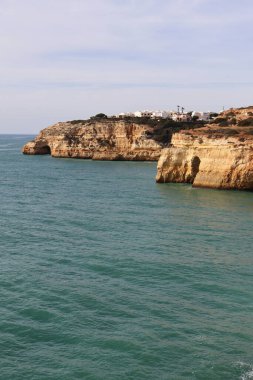 Güneşli bir kış gününde Atlantik Okyanusu 'nun yanındaki kayalıklarda beyaz binalar Algarve, Portekiz' deki Yedi Asılı Vadi Patikası boyunca uzanır..