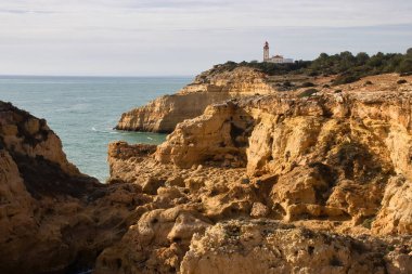Carvoeiro, Portekiz - 25 Aralık 2019: Atlantik Okyanusu üzerindeki Farol De Alfanzina Deniz Feneri 'ne giden Yedi Asılı Vadi Yolu üzerindeki kireçtaşı uçurumları.