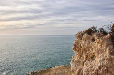 Atlantik Okyanusu üzerindeki bulutlar ve üzerinde kayalar olan küçük plajlar Güney Portekiz 'de bir kış öğleden sonra Yedi Asılı Vadi Patikası boyunca uzanır..