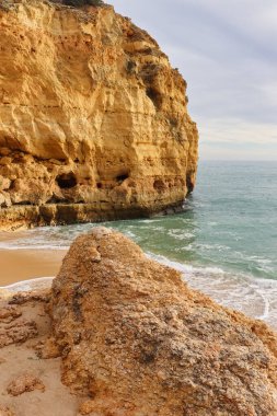Güney Portekiz 'de güneşli bir kış gününde, yedi sarkık vadi boyunca Kireçtaşı kayalıklarıyla kumlu sahilde rock yapmak..