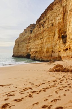 Sandy beach with footprints on a sunny winter day on a beach with cliffs in southern Portugal on the Seven Hanging Valleys Trail.