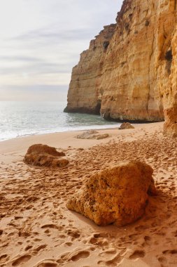 Kumlu bir sahilde kayalar güneşli bir kış gününde kayalıklar Güney Portekiz 'deki Yedi Asılı Vadi Yolu' nda..