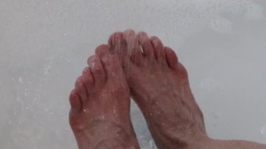 Su, küvette ayaklarına köpükler saçıyor..