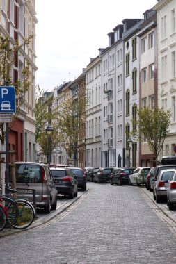 Bonn, Almanya - 16 Nisan 2021: Almanya 'nın Bonn kentinde bir bahar gününde kaldırım taşları üzerine dizilmiş binaların yanına park edilmiş arabalar.