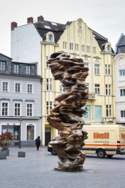 Bonn, Almanya - 16 Nisan 2021: Bonn, Almanya 'da bulutlu bir bahar gününde sarı bir binanın önündeki heykel.