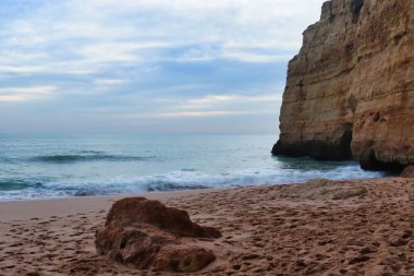 Güney Portekiz 'de bir kış akşamı bir uçurumla kumlu bir plajda rock yapmak..