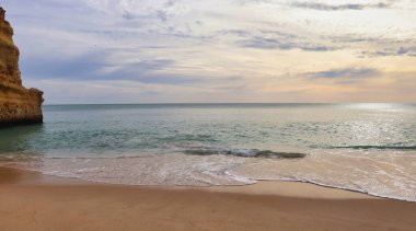 Güney Portekiz 'de sıcak bir kış öğleden sonrasında kumlu bir sahilden okyanusa bakıyorum..
