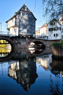 Bad Kreuznach, Almanya - 25 Nisan 2021: Eski Nahe Köprüsü 'ndeki tarihi bina ve Bad Kreuznach' ın aşağısındaki Nahe Nehri 'nin yansıması.