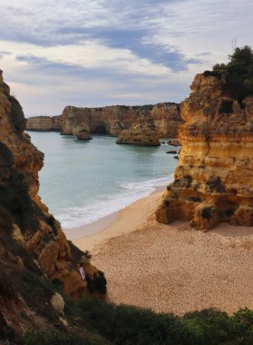 Güney Portekiz 'de bir kış günü kayalıklarla çevrili kumlu bir sahile bakan.