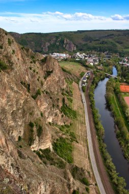 Bad Munster, Almanya - 9 Mayıs 2021: Bad Munster, Almanya 'da bir bahar gününde Rotenfels' te bir uçurumun dibindeki Nahe Nehri kıyısında bir yol kenarındaki üzüm bağı.