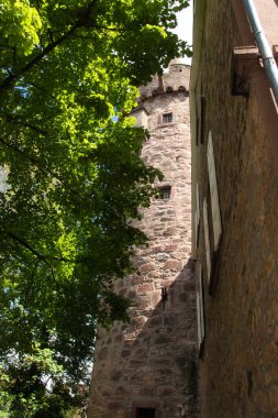 Weinheim, Almanya - 19 Mayıs 2021: Weinheim, Almanya 'da bir bahar günü yeşil ağaç bitişik duvar ve kule.