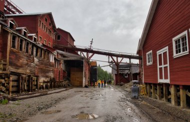 Kennecott, Alaska - 13 Temmuz 2023: Wrangell-St. Elias Ulusal Parkı 'ndaki Kennecott bakır madencilik kampında çamurlu yolun yanındaki kırmızı binalar.