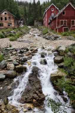 Kennecott, Alaska - 13 Temmuz 2023: Wrangell-St. Elias Ulusal Parkı 'ndaki Kennecott madeninde küçük bir şelalesi olan binalar arasında akarsu akışı.