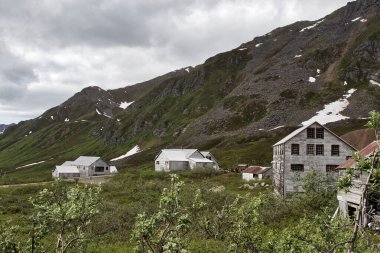 Palmer, Alaska - 14 Temmuz 2023 Alaska 'da bulutlu bir yaz gününde terk edilmiş Bağımsızlık Madeni' nde bir dağın yanındaki binalar.