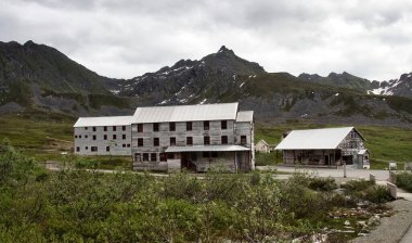 Palmer, Alaska - 14 Temmuz 2023: Alaska 'da bulutlu bir yaz gününde Independence Maden Eyalet Parkı' nın arka planında dağlar olan eski binalar.