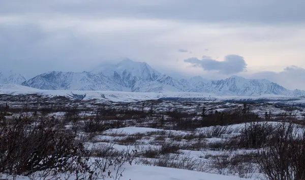 Delta Junction, Alaska yakınlarındaki karanlık bir kış öğleden sonra dağların üzerinden esen kar..