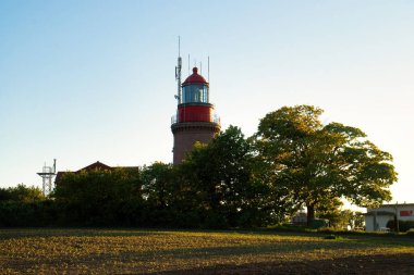 Bastorf, Almanya - 30 Mayıs 2021: Leuchtturm Buk, Almanya 'nın Bastorf kentindeki küçük bir deniz feneri, bir bahar akşamı Baltık Denizi kıyısında ağaçların arkasında.