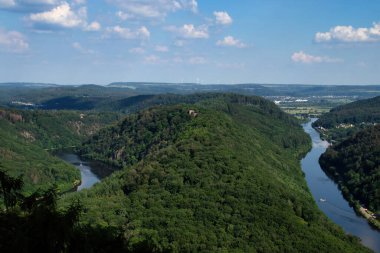 Mettlach, Germany - June 27, 2021: Montclair Castle ruins surrounded by green trees eclosed by the Saarschleife, a horseshoe bend in the Saar River on a spring day in Germany. clipart