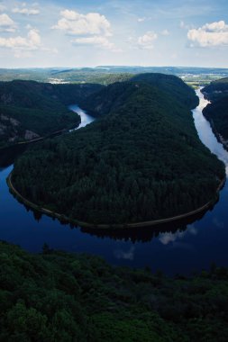 Almanya 'da güneşli bir bahar gününde Saar Nehri' nin gölgesinde at nalı kıvrılır..