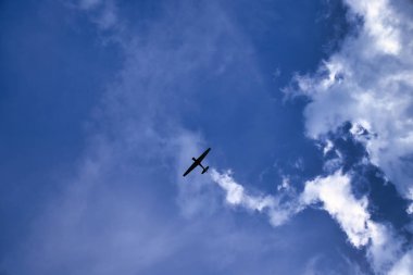 Almanya 'da bir bahar günü mavi gökyüzünde beyaz bulutlarla uçan uçak.