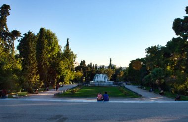 Atina, Yunanistan - 21 Eylül 2024: Yunanistan 'da bir sonbahar öğleden sonrasında yeşil ağaçlı bir parkta çeşme.