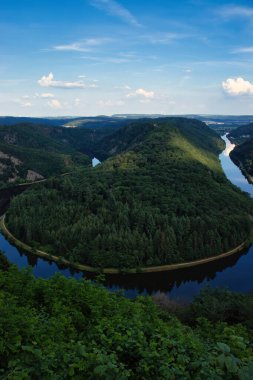 Almanya 'daki Saar Nehri' nde yeşil ağaçlarla çevrili tepelerden akan nehir..