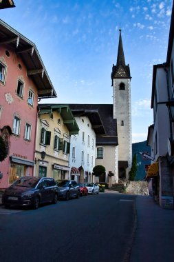 Avusturya 'nın başkenti Golling an der Salzach' ta 15 Haziran 2021: Avusturya 'da bir bahar akşamı, renkli binaların bulunduğu bir sokakta kilise.