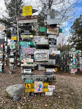 Watson Lake, Canada - October 9, 2024: Paths through signs and license signs on wood posts at Sign Post Forest on the Alaska Highway in Canada on a spring day.  clipart