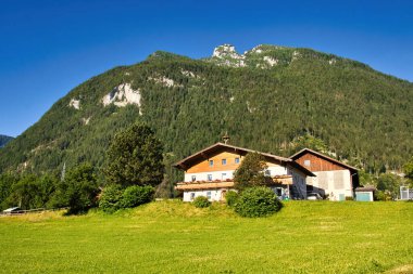 Golling an der Salzach, Austria - June 16, 2021: House in front of a mountain in Golling an der Salzach, Austria on a bright spring morning. clipart