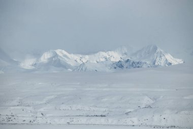 Alaska 'daki Denali Otobanı' nda bulutlu bir bahar gününde dağlarda parlayan ışık.. 