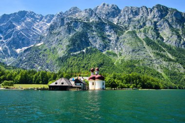 Bavaria, Germany - June 16, 2021: Mountain behind Pilgrimage Church of St. Bartholomew on a sunny spring day at Konigssee in Bavaria, Germany. clipart