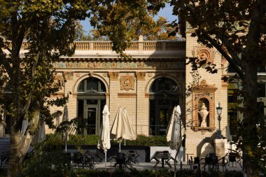 Budapeşte, Macaristan - 26 Ekim 2021: Macaristan 'ın başkenti Budapeşte' deki bir parkta Macar Milenyumu 'nun dışındaki masalarda şemsiyeler.