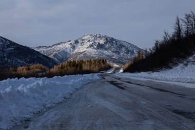 Alaska 'da bulutlu bir kış gününde Richardson Karayolu' nun arkasındaki güneşi aydınlatan dağ. 