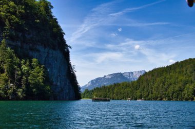 Bavaria, Germany - June 16, 2021: Boats on water below mountains on a sunny spring day at Konigssee in Bavaria, Germany. clipart