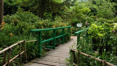 Fransa 'nın Giverny şehrinde bir yaz günü Monet' s Garden 'da bitkiler ve çiçekler arasında köprü.