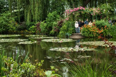 Giverny, Fransa - 23 Haziran 2021: Fransa 'nın Giverny kentinde bir yaz günü Monet' in bahçesinde zambaklarla birlikte göletin yanındaki pembe güller.