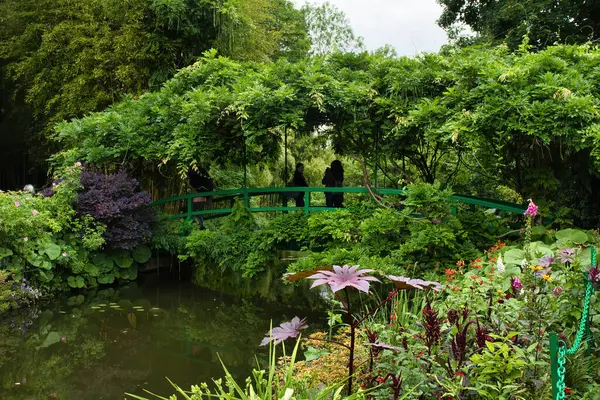 Giverny, Fransa - 23 Haziran 2021: Fransa 'nın Giverny şehrinde bir yaz günü Monet' in bahçesindeki yeşil köprü etrafındaki yeşil bitkiler ve ağaçlar.