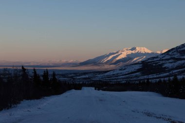 Donnelly Kubbesi 'nin yanındaki yol. Arka planda güneş parlıyor. Delta Kavşağı, Alaska yakınlarında bir kış öğleden sonrası.. 