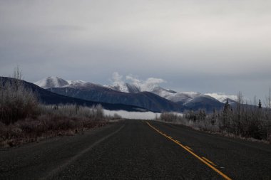 Kanada 'daki Alaska Otoyolu' nda bir sonbahar gününde dağların ve bulutların altında sis. 