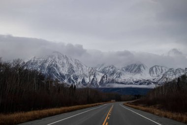 Alaska Otoyolu karlı dağlara ve bulutlara götürür Kanada 'da bir sonbahar gününde. 