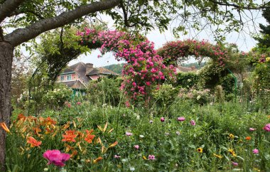 Giverny, Fransa - 23 Haziran 2021: Fransa 'da bir yaz gününde arka planda Monet' nin evi olan bir bahçede çiçekler.