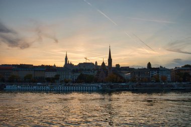 Budapeşte, Macaristan - 26 Ekim 2021: Macaristan 'ın Budapeşte kentinde renkli bir gökyüzü ile Tuna Nehri yakınındaki binalar.