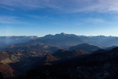 Dağlardaki ve tepelerdeki aydınlık ve gölgeler Avusturya Alplerindeki bir teleferiğin camından süzülüyor puslu bir sonbahar akşamında..
