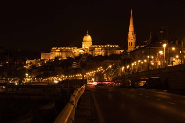 Budapeşte, Macaristan - 25 Ekim 2021 Macaristan 'da karanlık bir yaz gecesinde karayolu üzerinde arabaları ve ışıkları olan Buda Şatosu.